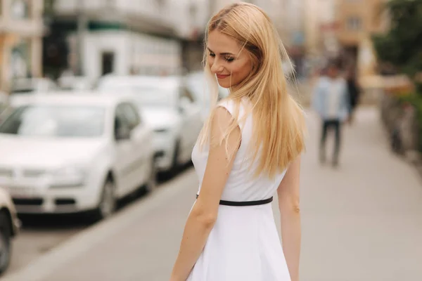 Prachtig blond haar vrouw in witte jurk dans in het centrum van de stad — Stockfoto