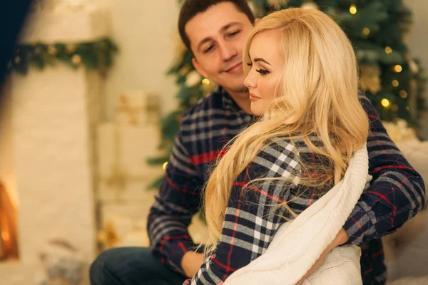 Happy couple in holiday spirit showing affection for one another. Dressed in plaid clothes. Gentle pregnant woman