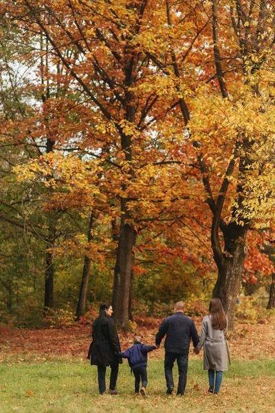 Passeggiata in famiglia in una foresta autunnale con foglie cadute. Madre padre e due figlie nel parco — Foto Stock