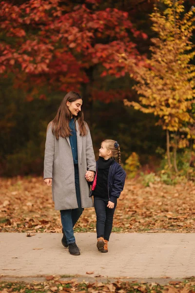 Due sorelle passeggiano nel parco in autunno. L'infanzia. stagione e la gente consept-felice famiglia — Foto Stock