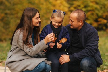 Baba ve iki kızı ormanın içinde. Sonbahar hava ve renkli arka plan. Mutlu bir aile. İki kız kardeşi baba için onların sevgi göster