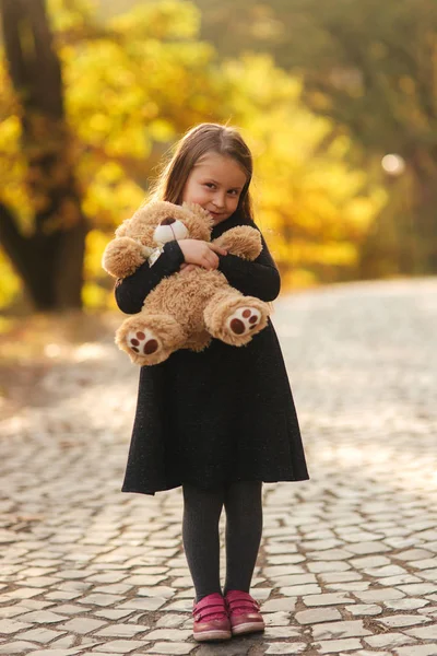 손에서 테 디 베어를 보유 하 고 있는 어린 소녀의 초상화. 행복 어린이 공원입니다. 카메라에 아름 다운 여자 모델 미소 — 스톡 사진