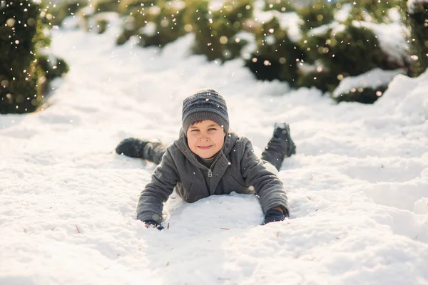 Um menino de roupas de inverno salta para a neve — Fotografia de Stock