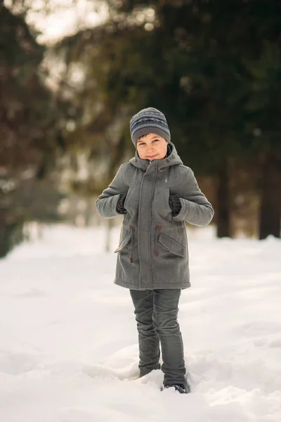 Ein kleiner Junge spaziert bei Winterwetter durch den Park, spielt Schneebälle und freut sich. Warten auf Weihnachtsstimmung — Stockfoto