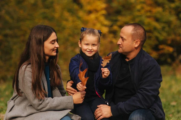 父亲和两个女儿在森林里。秋天的天气和五颜六色的背景。幸福的家庭。两个妹妹向爸爸示爱 — 图库照片