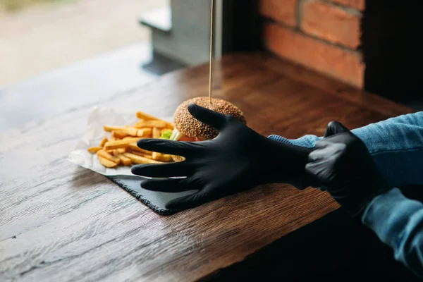 Hombre con guantes negros toma una hamburguesa vegetariana en sus manos — Foto de Stock