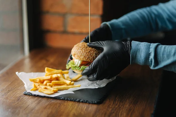 Man in black gloves takes a burger in his hands. Vegetarian burger with vegetables. Fresh healthy food