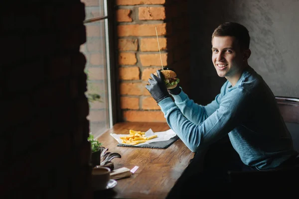 El hombre con guantes negros toma una hamburguesa en sus manos. Hamburguesa vegetariana con verduras. Alimentos frescos y saludables — Foto de Stock