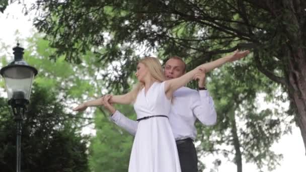 Una giovane coppia che cammina nel parco. Il buon divertimento e gioire. Vestiti bianchi e neri — Video Stock