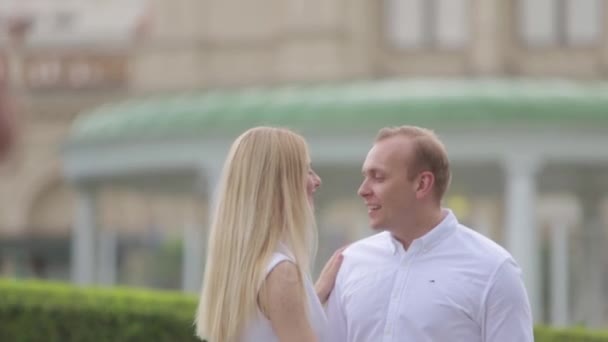 Mann und Frau tänzeln im Park vor dem großen Palast. Liebesgeschichte eines charmanten Paares. schöner grüner Hintergrund — Stockvideo