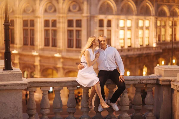 La femme et le mari sont assis à la frontière devant des lumières. Soirée en ville — Photo