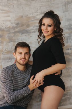 Mutlu bir adam onun handr onun hamile eşi karnına koydu. Genç aile Studio. Bir bebek için beklemek birleştirmek