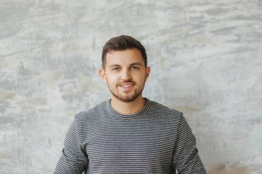 Studio gri arka plan üzerinde durabilen sakallı yakışıklı adam. Kameraya gülümse