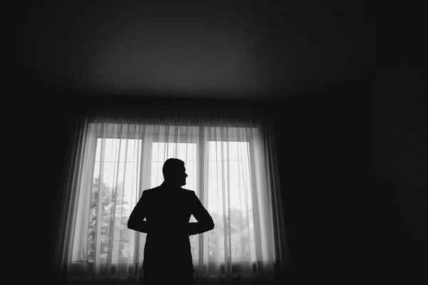 Man stand in front of window. Silhouette of young man. Black and white picture — Stock Photo, Image