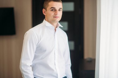 Damat takım elbiseli evde giyindi. Şirin damat bir fotoğrafçısına poz