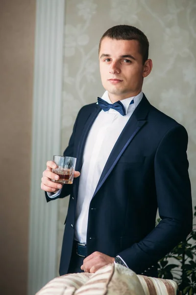 Homem bonito em terno de casamento segurar um copo de uísque — Fotografia de Stock