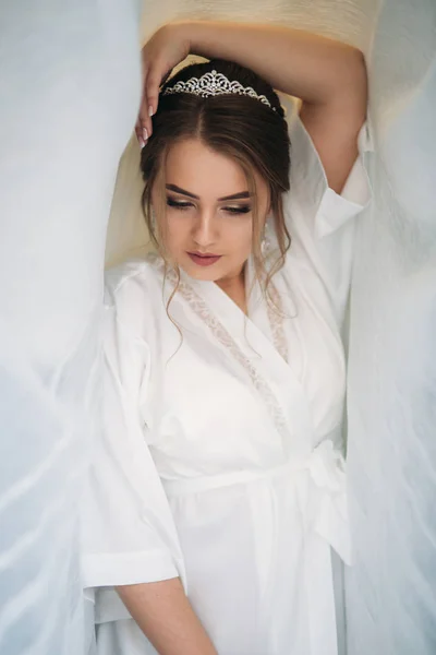 Πορτρέτο της νύφης σε μια ρόμπα κάτω από την λευκή κουρτίνα — Φωτογραφία Αρχείου