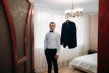 Damat takım elbiseli evde giyindi. Şirin damat bir fotoğrafçısına poz