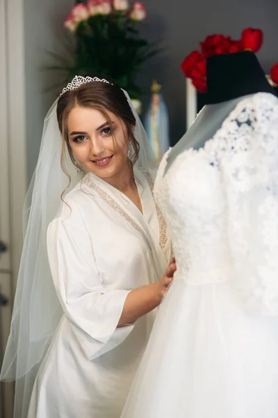 Linda novia vestida en casa en un vestido de novia — Foto de Stock