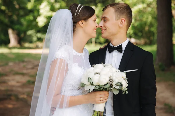 Os recém-casados estão andando no parque no dia do casamento. Apenas um casal. noivo e noiva no fundo verde — Fotografia de Stock