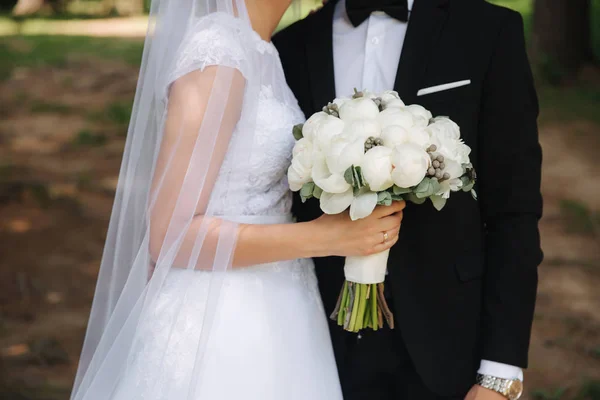 Gli sposi stanno camminando nel parco il giorno del matrimonio. Solo una coppia sposata. Sposo e sposa su sfondo verde — Foto Stock