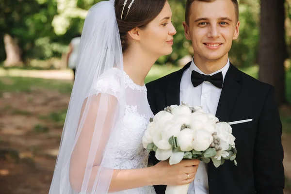 Os recém-casados estão andando no parque no dia do casamento. Apenas um casal. noivo e noiva no fundo verde — Fotografia de Stock