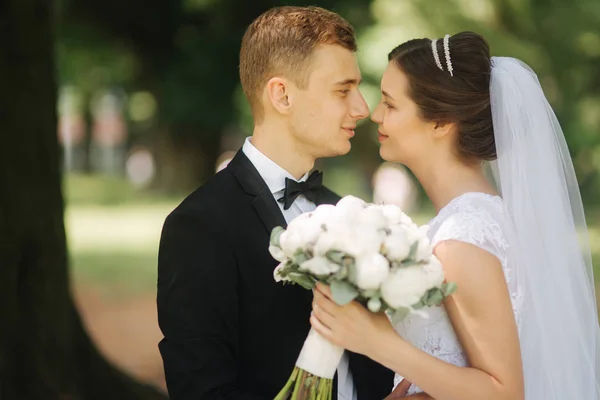 Os recém-casados estão andando no parque no dia do casamento. Apenas um casal. noivo e noiva no fundo verde — Fotografia de Stock