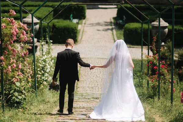 Mariée et marié marchent dans le parc près du grand château — Photo