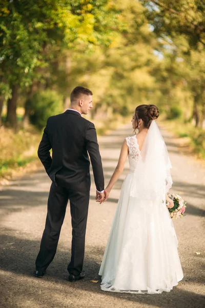 Casal romântico de recém-casados andando no meio do beco — Fotografia de Stock