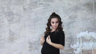 Hamile kadın gri duvarın önünde dur. Stüdyo. Modeli