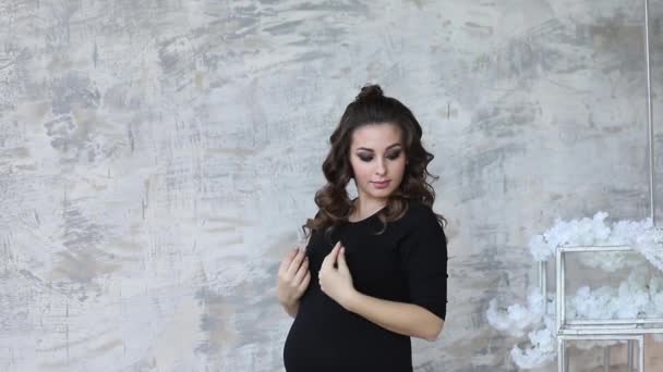 Schwangere stehen vor grauer Wand. Studio. Modell — Stockvideo