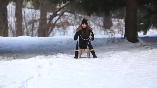 Beautiful girl in black clothes ride on a snowy mountains by the sled. Sledding — Stock Video