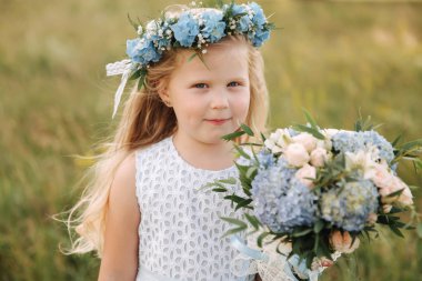 Çelenk ve buket stand alanında büyük ağacın önünde ile gökyüzü mavi elbiseli küçük kız