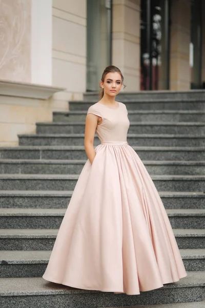 Elegante morena em pé nas escadas ao lado do hotel. Modelo de moda em vestido de noite — Fotografia de Stock