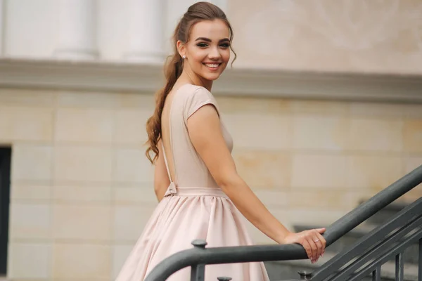 Die elegante Brünette steht auf der Treppe neben dem Hotel. Mode-Model im Abendkleid — Stockfoto