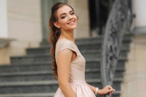 Die elegante Brünette steht auf der Treppe neben dem Hotel. Mode-Model im Abendkleid — Stockfoto