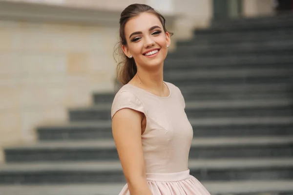 Die elegante Brünette steht auf der Treppe neben dem Hotel. Mode-Model im Abendkleid — Stockfoto