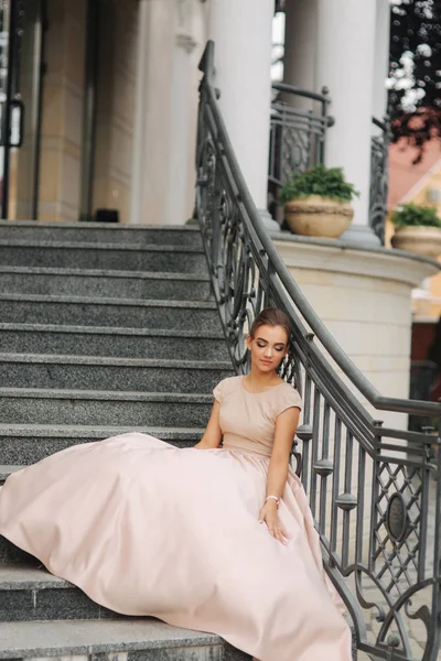 Fashion model sits on the stairs by the hotel. Beautiful lady with modern hairstyle — Stock Photo, Image