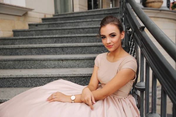 Modelka siedzi na schodach przez hotel. Piękna Pani z nowoczesną fryzurę — Zdjęcie stockowe