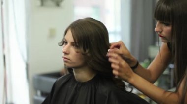Kuaför bir saç modeli için bir kadın yapıyor. Saç yakın çekim. Makas ve stilist, tarak. Genç bir kız güzel saç
