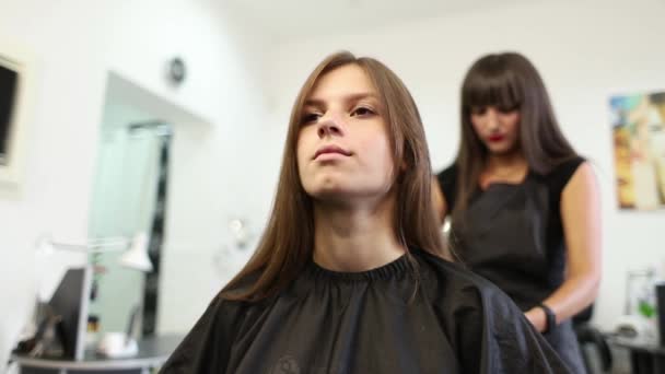 Mujer joven en el salón de belleza cortada por una peluquera — Vídeo de stock