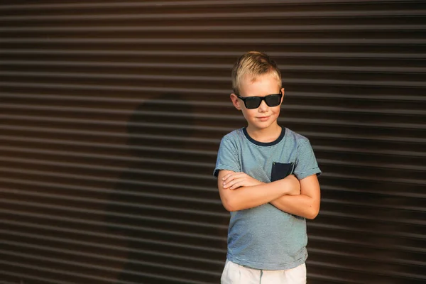 Gutaussehender Junge lächelt und posiert für den Fotografen. Junge hat Sonnenbrille. Junges Modell — Stockfoto