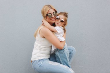 Güzel mothe kızıyla birlikte. Sarışın kadın. Gri arka plan. En iyi dostlar.