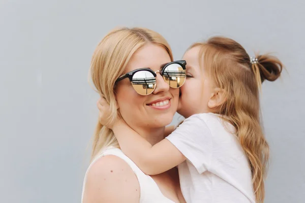 Uma bela traça com a filha. Cabelo loiro feminino. Fundo cinzento. Melhores amigos — Fotografia de Stock