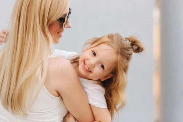 Schöne mothe mit ihrer Tochter. blonde Haare weiblich. grauer Hintergrund. beste Freunde — Stockfoto