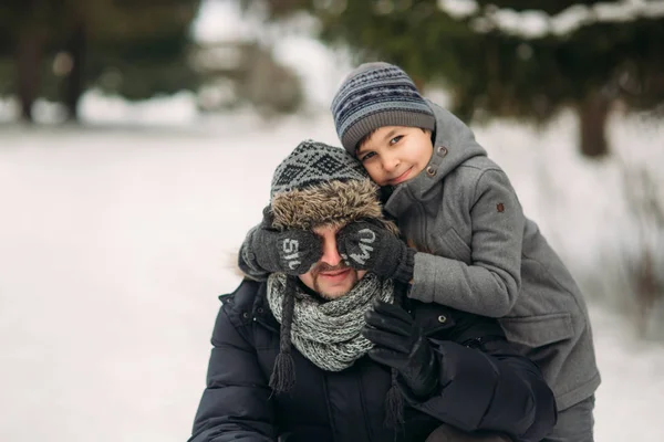 Boldog apa és fia sétál a parkban, a havas téli időjárás — Stock Fotó