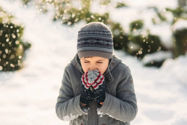 Een jongen verwarmt zijn handen van de kou in de winter — Stockfoto
