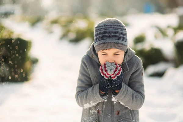 Um menino aquece as mãos do frio no inverno — Fotografia de Stock
