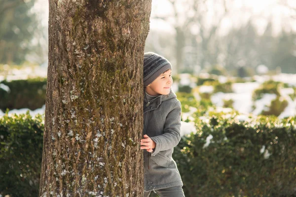 Kleiner hübscher Junge spielt im Park mit Schnee. Weihnachtsstimmung — Stockfoto