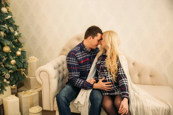 Glückliches Paar in Urlaubsstimmung, das Zuneigung füreinander zeigt. gekleidet in karierte Kleidung. sanfte Schwangere. frohes neues Jahr — Stockfoto